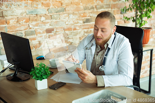 Image of Caucasian doctor consulting for patient, explaining recipe for drug, working in cabinet