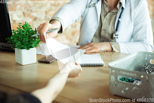 Image of Close up of caucasian doctor consulting for patient, explaining recipe for drug, working in cabinet