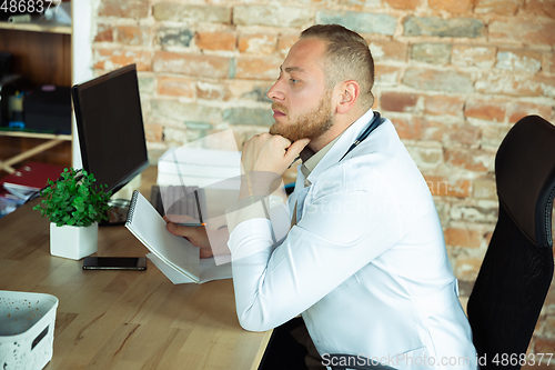 Image of Caucasian doctor consulting for patient, explaining recipe for drug, working in cabinet