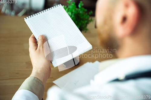 Image of Close up of caucasian doctor consulting for patient, explaining recipe for drug, working in cabinet