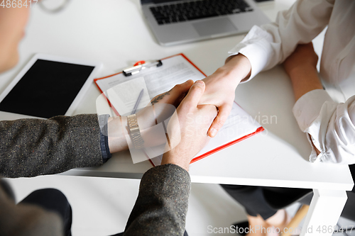 Image of Close up of male and female hands holding at the table with sheets, laptop, smartphone, office