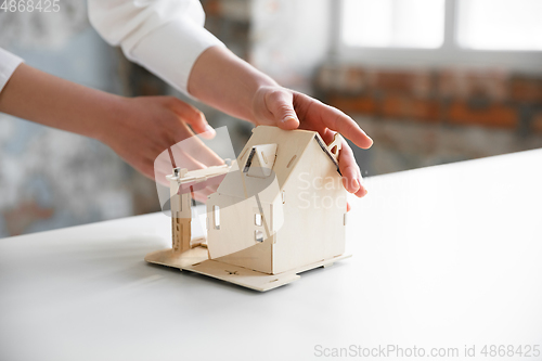 Image of Close up of future house model. Female estate agent showing new home to a young man after a discussion on house plans, moving, new home concept