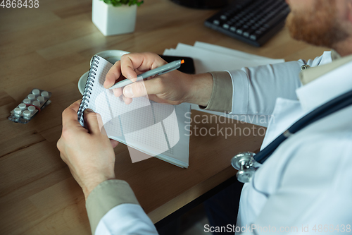 Image of Caucasian doctor consulting for patient, explaining recipe for drug, working in cabinet