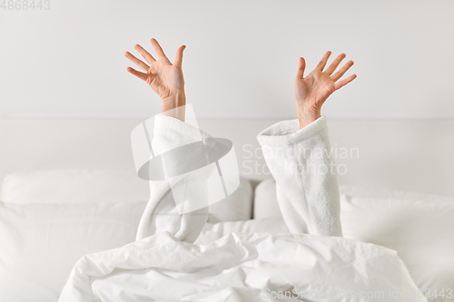 Image of hands of woman lying in bed and stretching