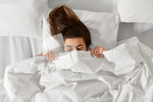 Image of woman lying in bed under white blanket or duvet