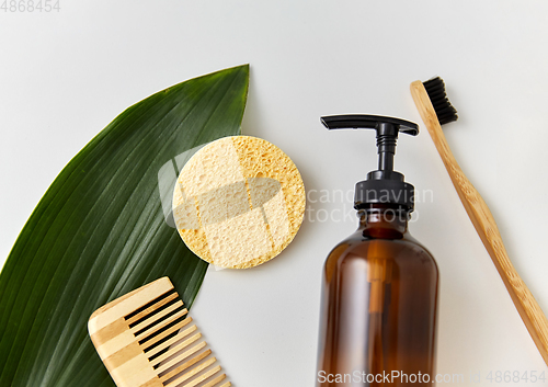 Image of comb, sponge, liquid soap or shower gel and leaf