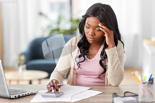 Image of woman with calculator and papers working at home