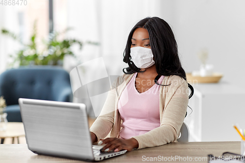 Image of woman in mask with laptop working at home office