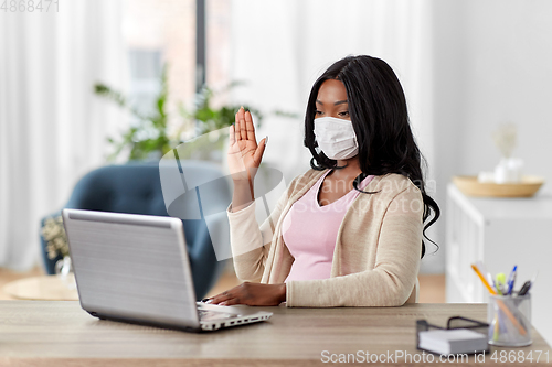 Image of woman in mask with laptop has video call at home