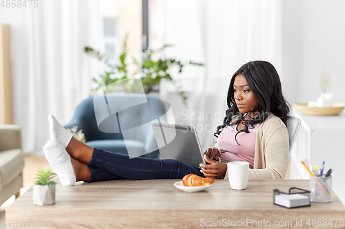 Image of african woman with laptop working at home office