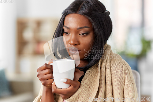Image of sick african amercian woman drinking tea at home