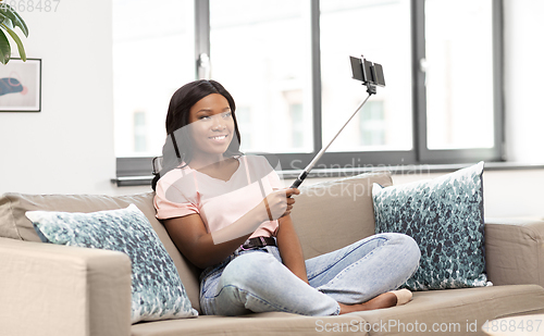 Image of happy african american woman taking selfie at home