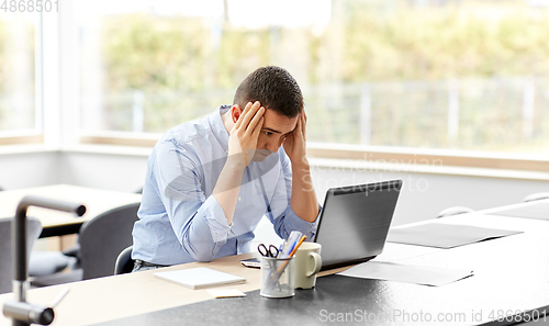 Image of stressed man with laptop working at home office