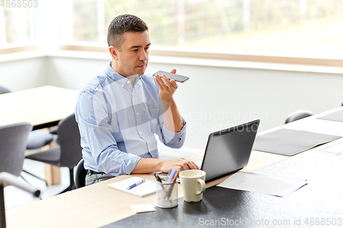 Image of man with smartphone and laptop at home office