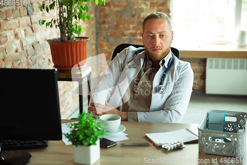 Image of Caucasian doctor consulting for patient, explaining recipe for drug, working in cabinet