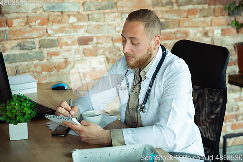 Image of Caucasian doctor consulting for patient, explaining recipe for drug, working in cabinet