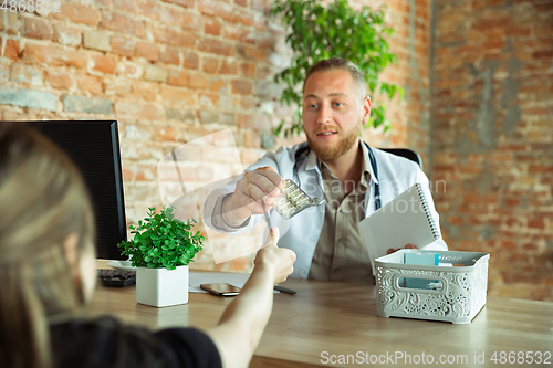 Image of Caucasian doctor consulting for patient, explaining recipe for drug, working in cabinet