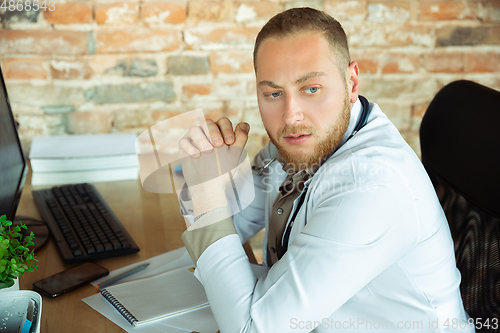 Image of Caucasian doctor resting after consulting for patient, working in cabinet