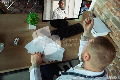 Image of Caucasian doctor has online conference with colleague, consulting, working in cabinet