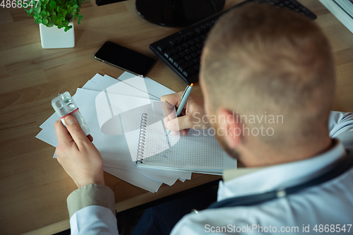 Image of Caucasian doctor consulting for patient, explaining recipe for drug, working in cabinet