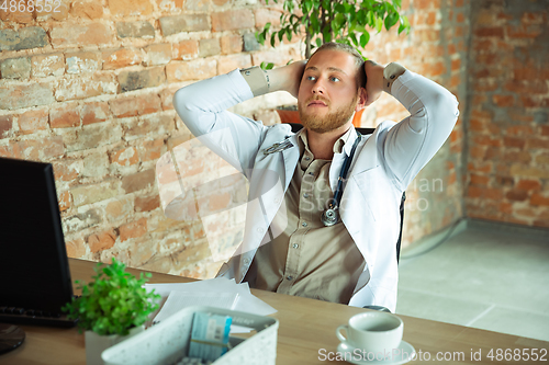 Image of Caucasian doctor resting after consulting for patient, working in cabinet