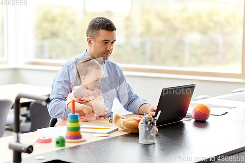 Image of father with baby working on laptop at home office