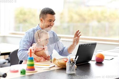 Image of father with baby working on laptop at home office