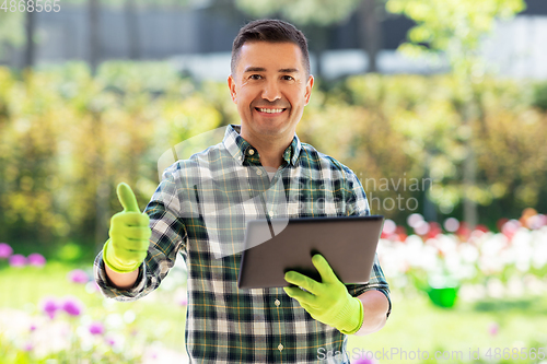 Image of man with tablet pc showing thumbs up at garden