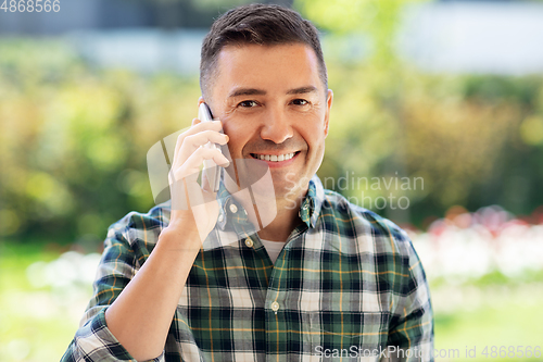 Image of happy man calling on smartphone at summer garden