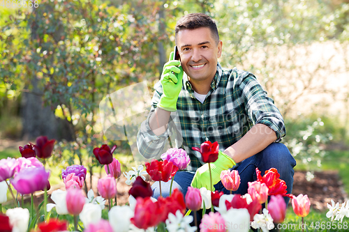 Image of man with flowers calling on smartphone at garden