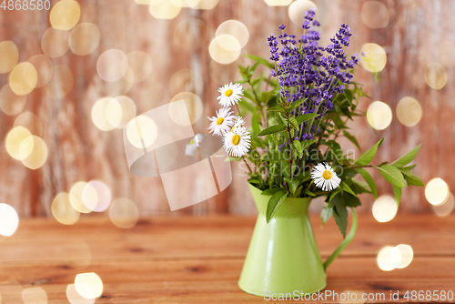 Image of bunch of herbs and flowers in green jug on table