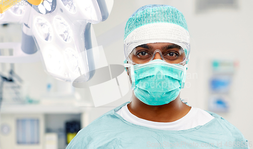 Image of indian male surgeon in mask over operating room