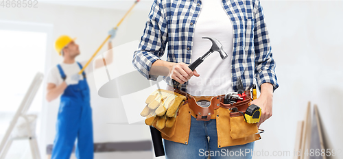 Image of woman with hammer and working tools on belt