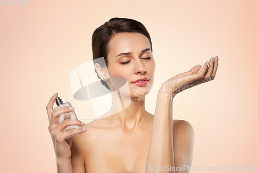 Image of happy woman smelling perfume from her wrist