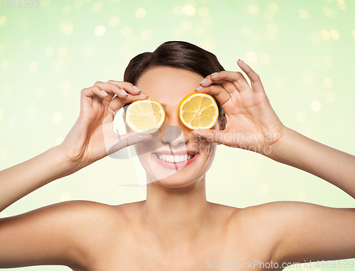 Image of beautiful woman making eye mask of lemon slices