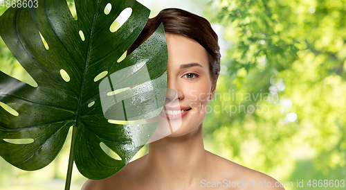 Image of beautiful young woman with green monstera leaf