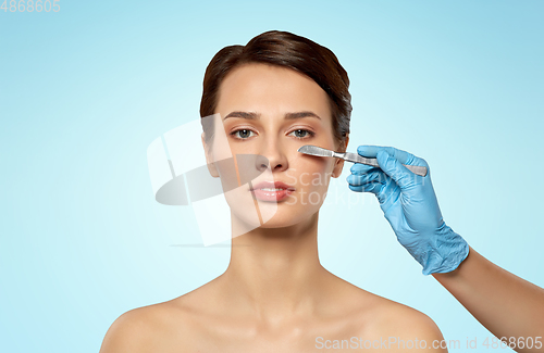 Image of beautiful young woman and hand with scalpel