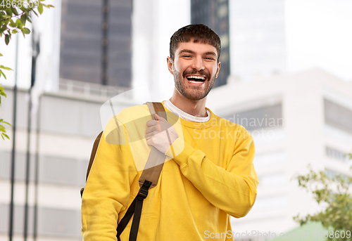 Image of happy smiling young man with backpack in city