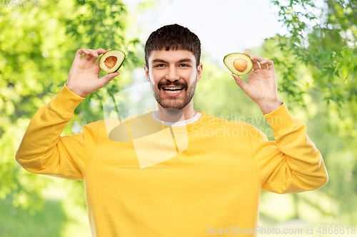 Image of happy young man in yellow sweatshirt with avocado