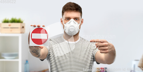 Image of man in respirator mask showing stop sign