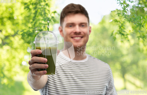 Image of man drinking green smoothie from disposable cup