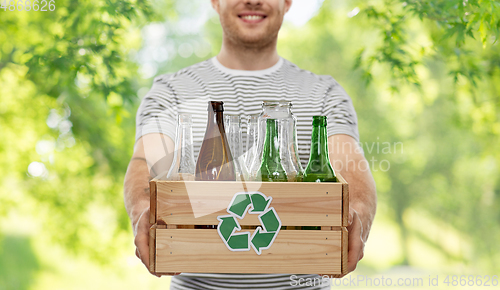 Image of smiling young man sorting glass waste