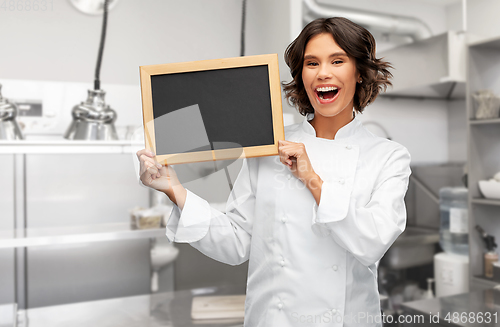 Image of smiling female chef holding black chalkboard