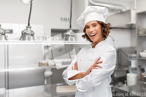 Image of smiling female chef in toque with crossed arms