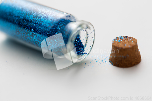 Image of blue glitters in bottle over white background