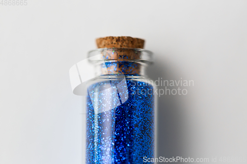 Image of blue glitters in bottle over white background