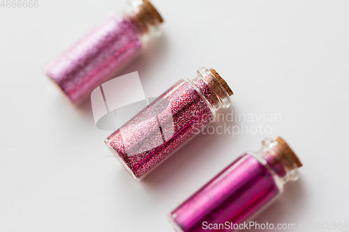 Image of red glitters in bottles over white background