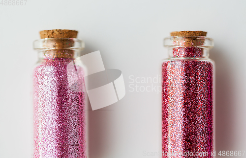 Image of red glitters in bottles over white background