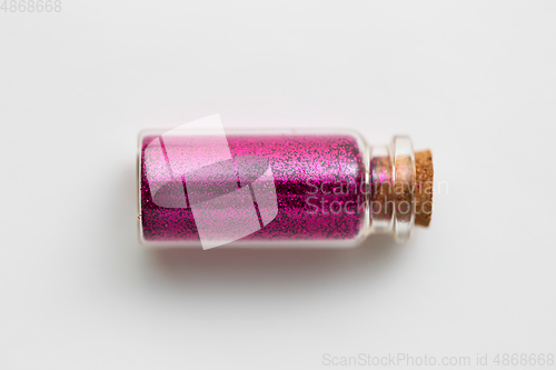 Image of pink glitters in bottle over white background