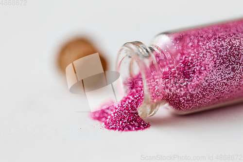 Image of pink glitters poured from small glass bottle